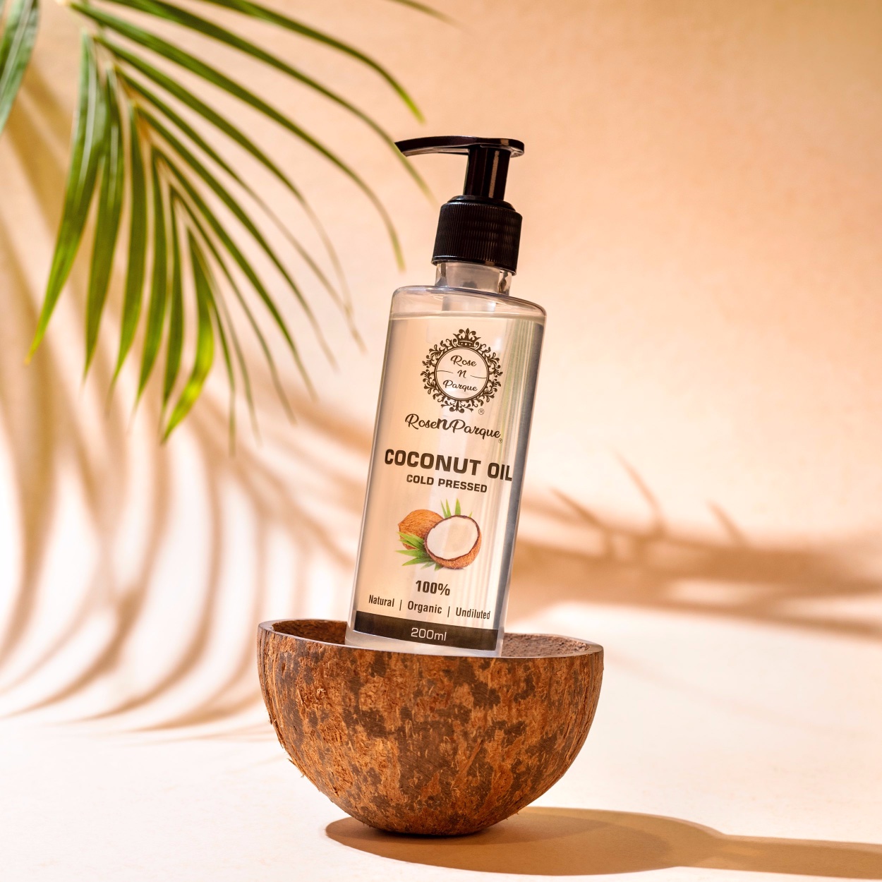 Transparent pump bottle of 100% cold-pressed coconut oil placed in a wooden bowl.