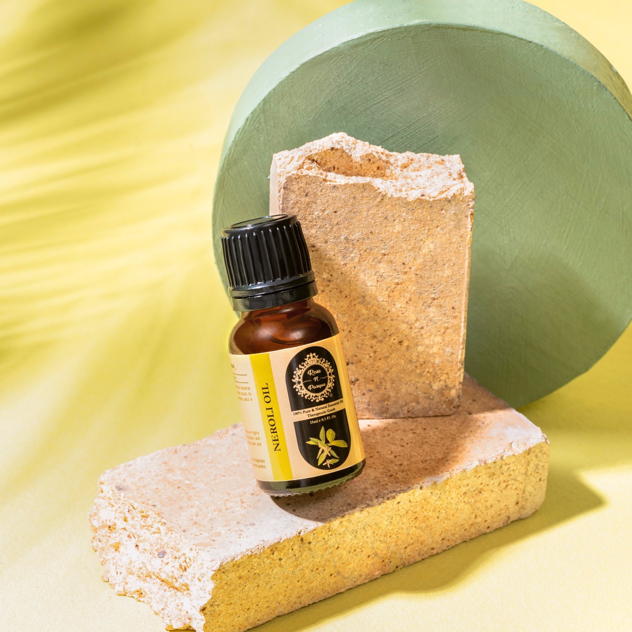 Tea tree essential oil bottle placed on textured stone blocks with a green circular background.