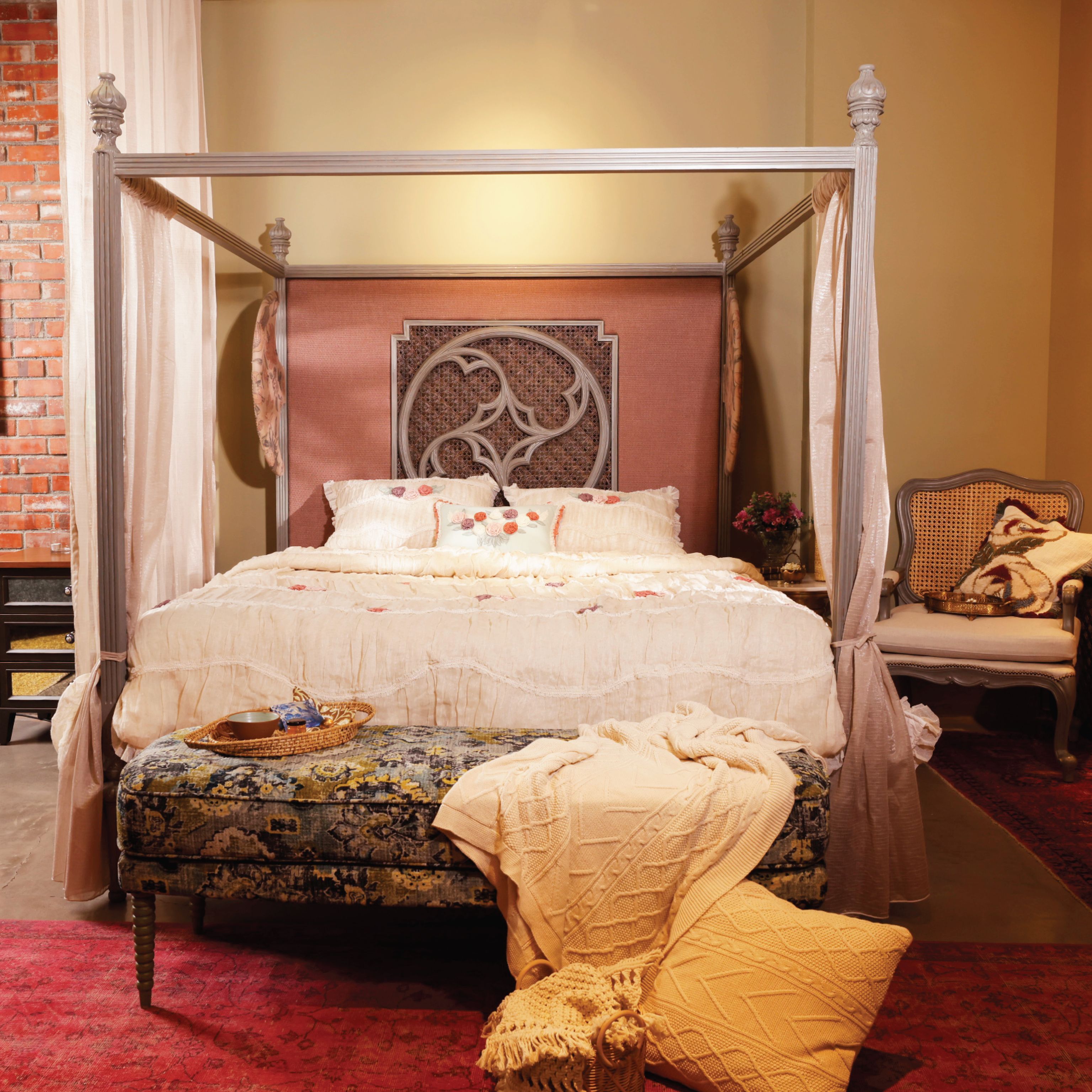 A four-poster canopy bed with a decorative headboard and soft bedding in a styled interior.