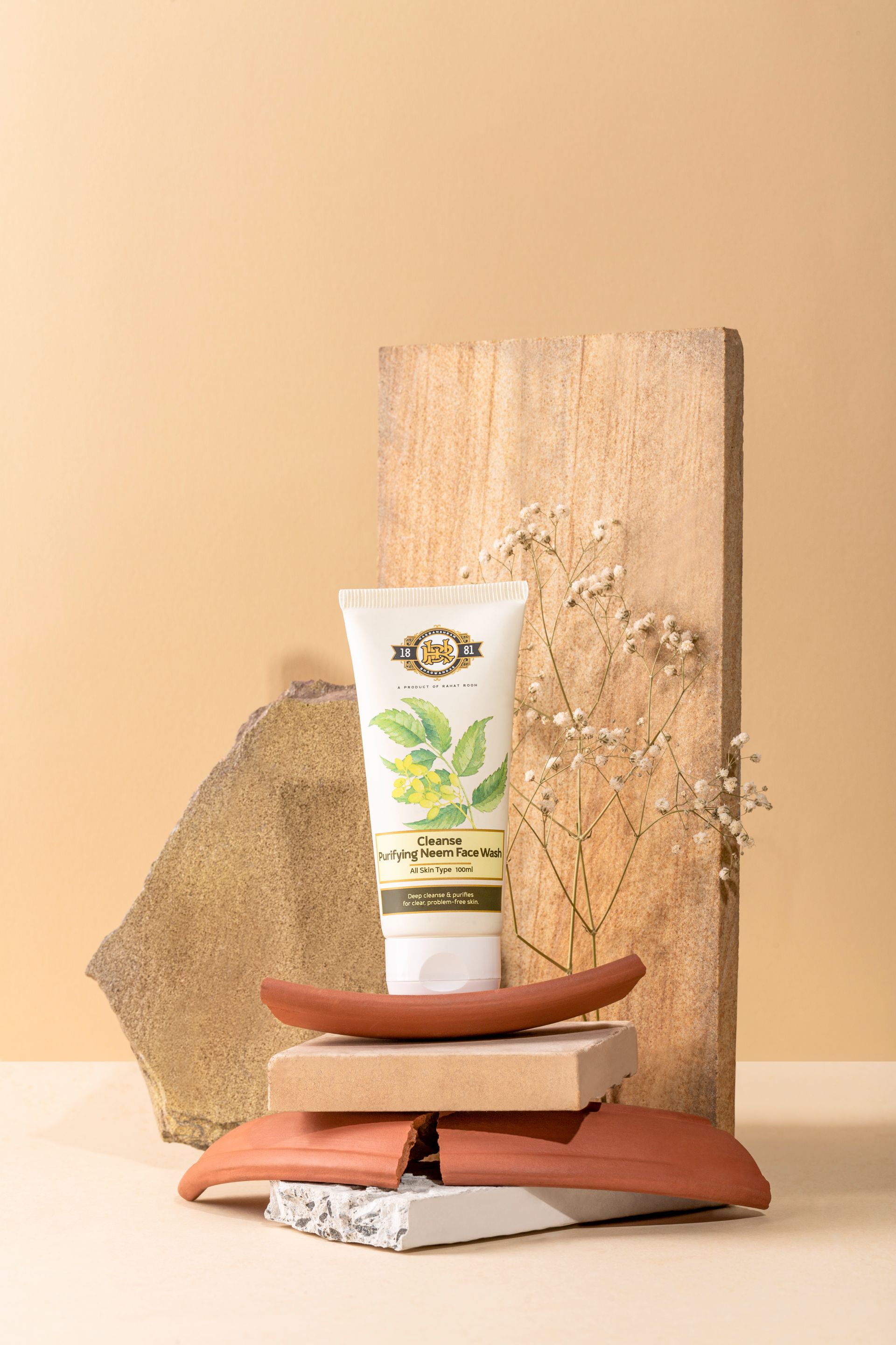 Tube of purifying herbal face wash with mint leaves design on a stacked arrangement of clay and wood.
