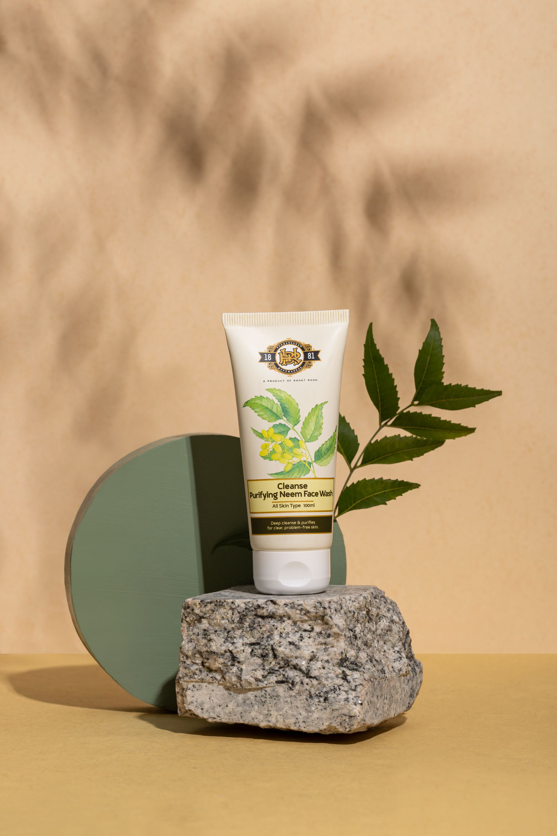 Tube of purifying herbal face wash placed on a textured stone and circular backdrop.