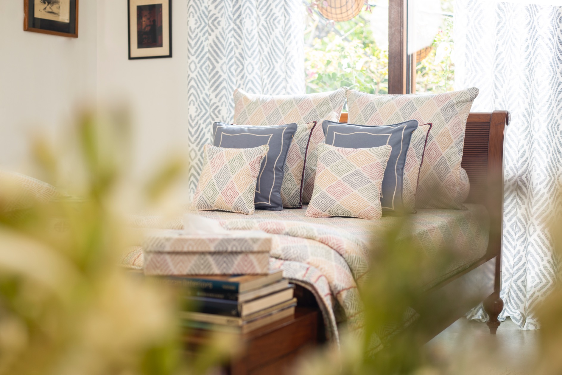 A quilted bedspread with decorative cushions arranged on a wooden bed frame in a well-lit room.