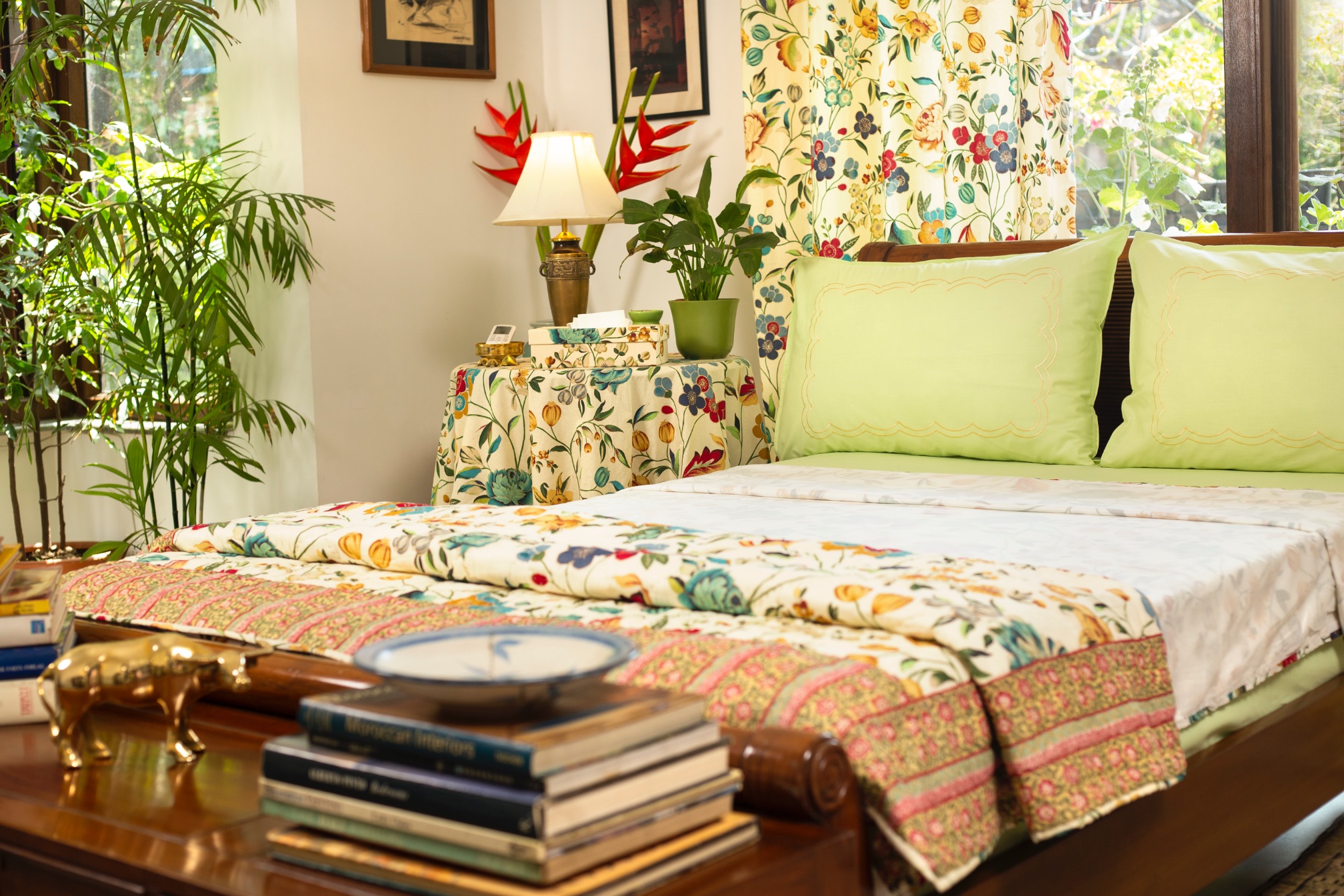 Bed with floral patterned bedding and green pillows in a well-decorated room.
