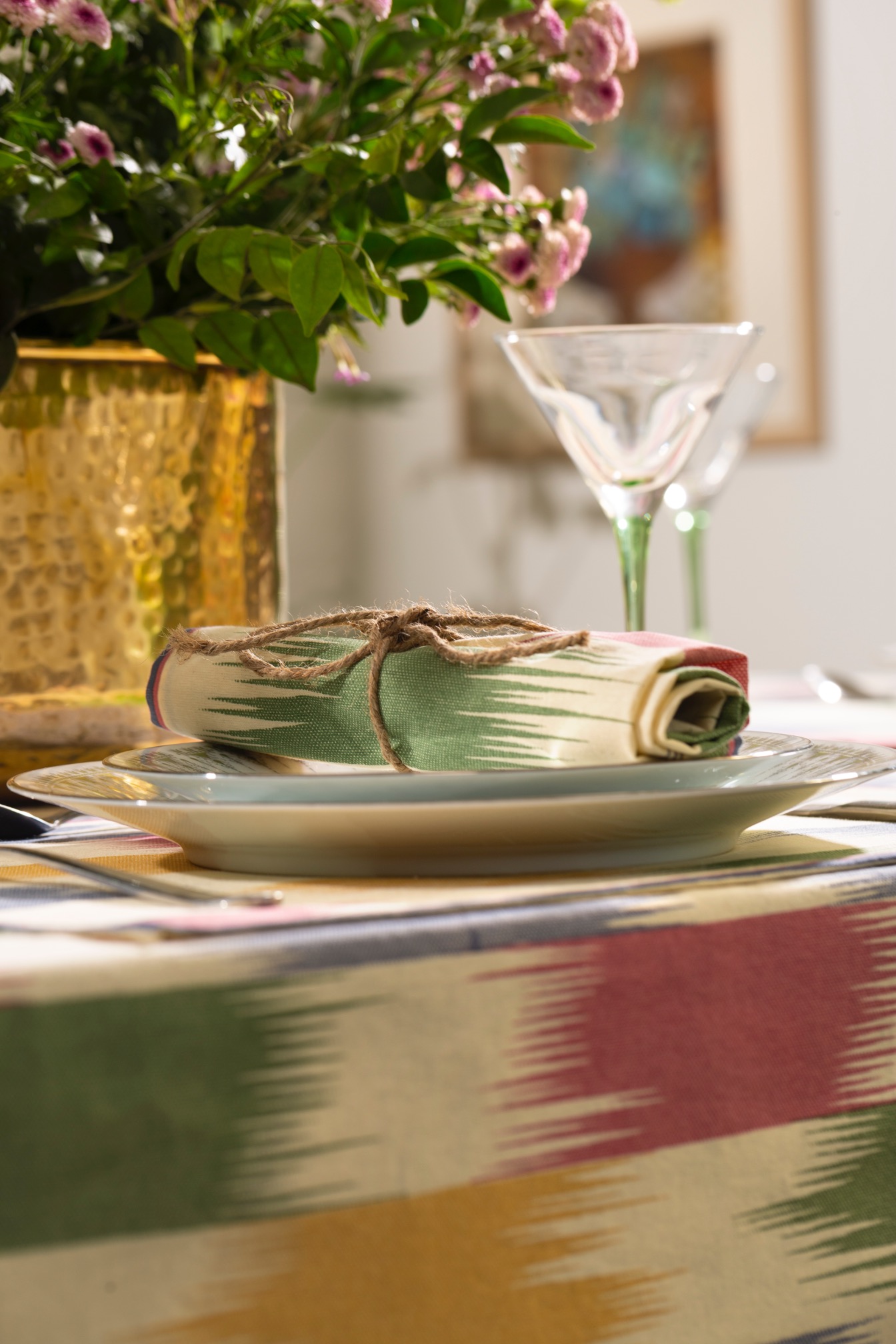A neatly arranged table setting featuring a decorative napkin and a plate on a patterned tablecloth.