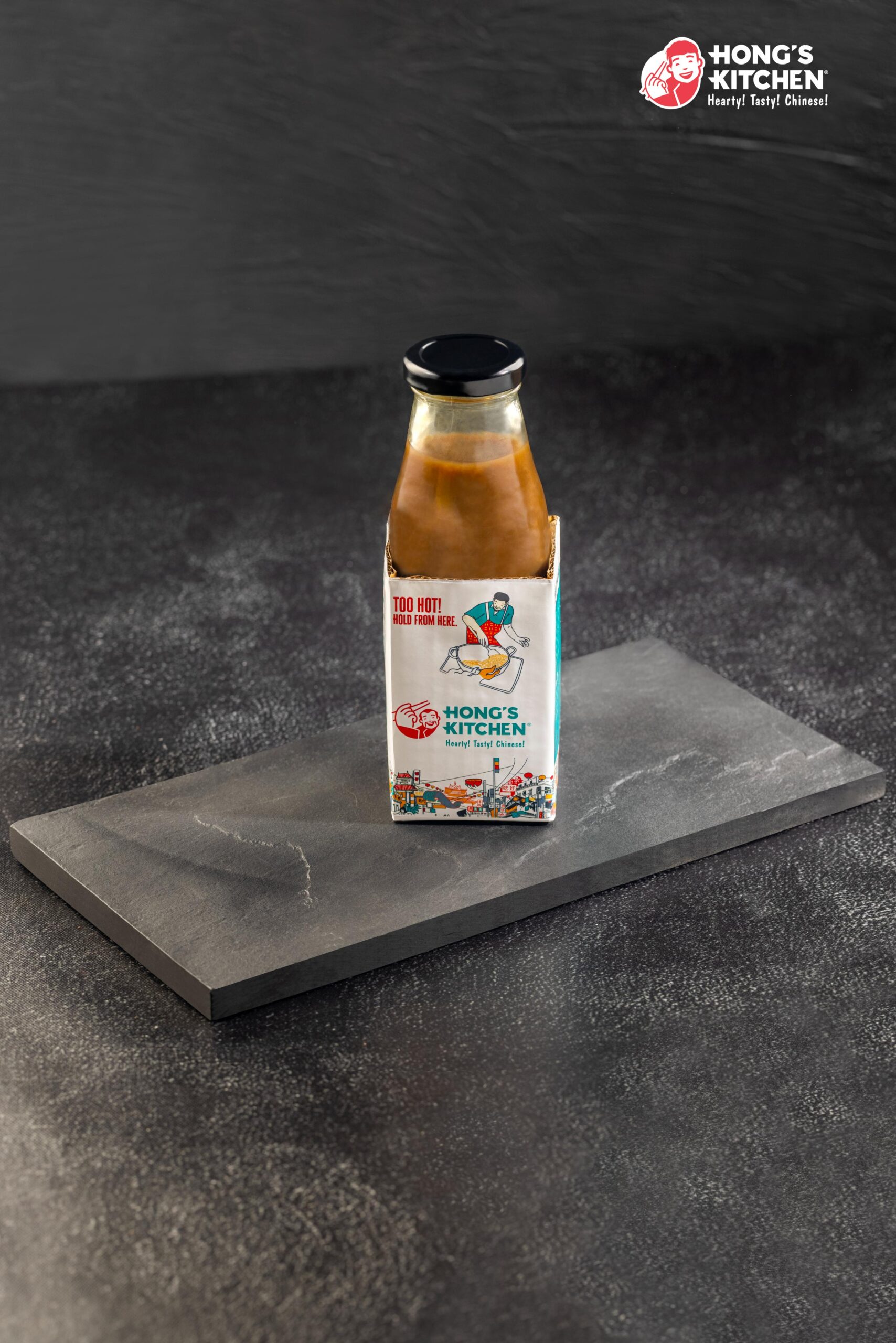 Bottle of Hong's Kitchen sauce with a colorful label placed on a dark surface.