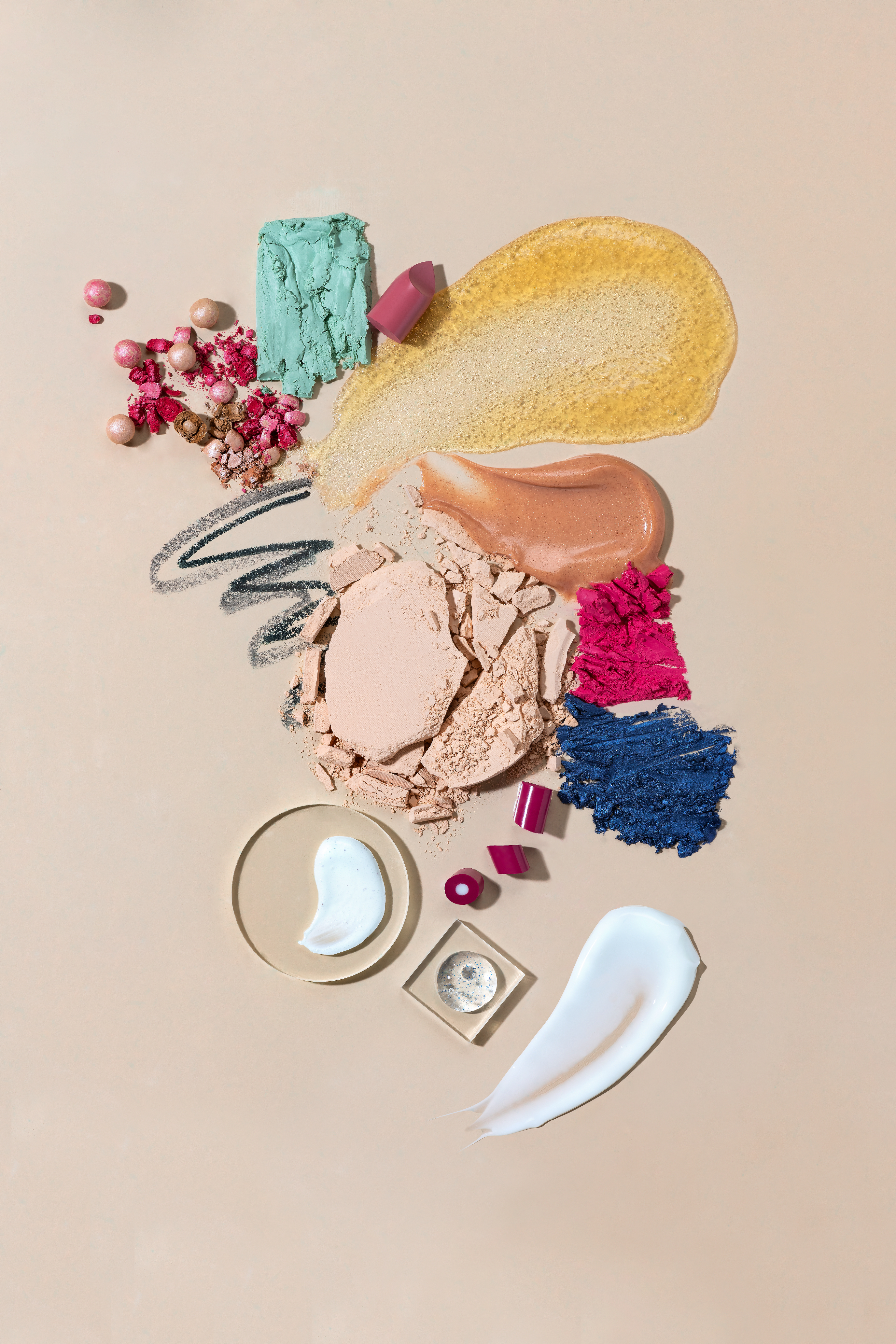An arrangement of various makeup products including powders, creams, and pigments on a neutral background.