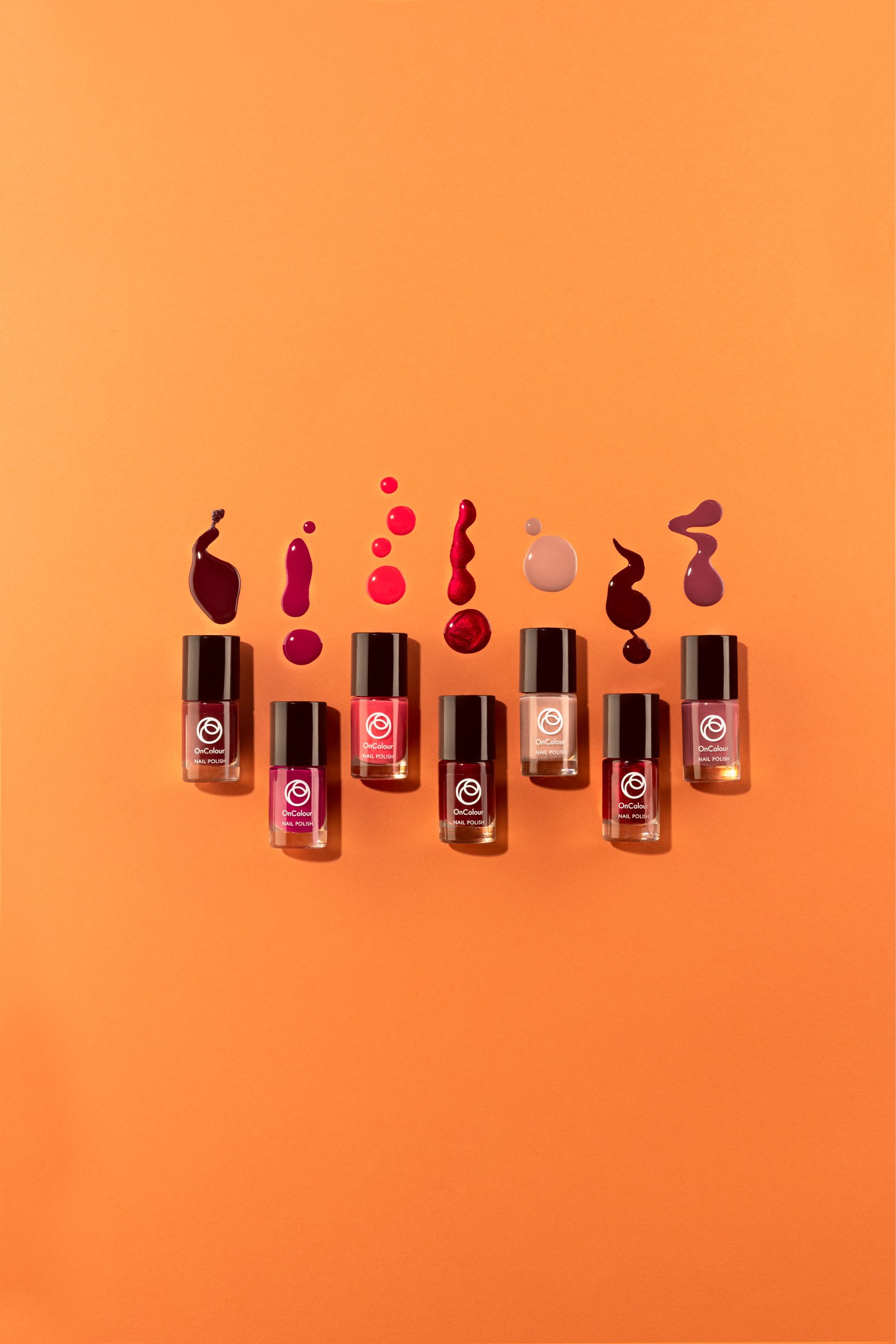 Eight nail polish bottles arranged in a row with corresponding color swatches on an orange background.