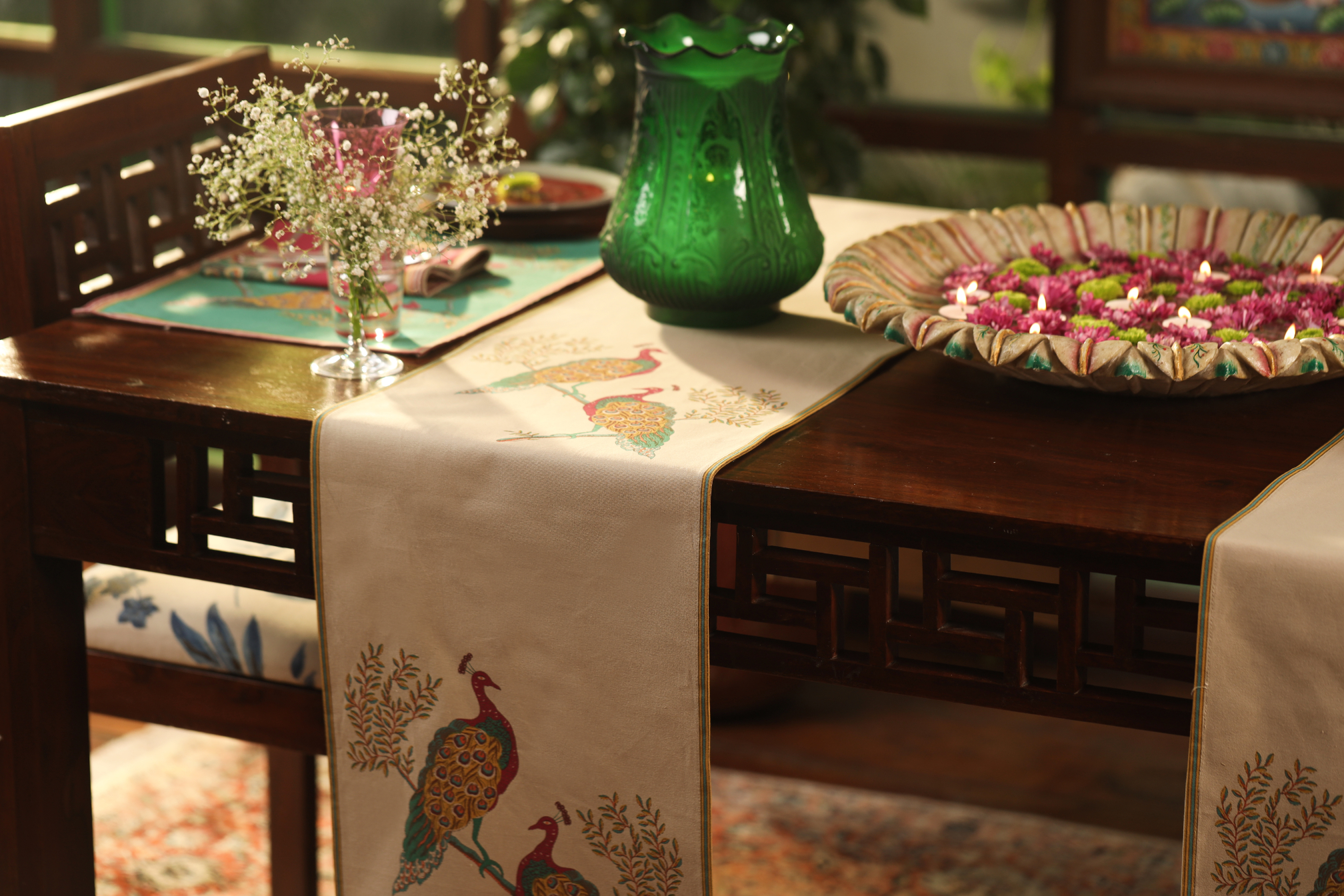 Embroidered table runner featuring peacock designs on a wooden dining table.