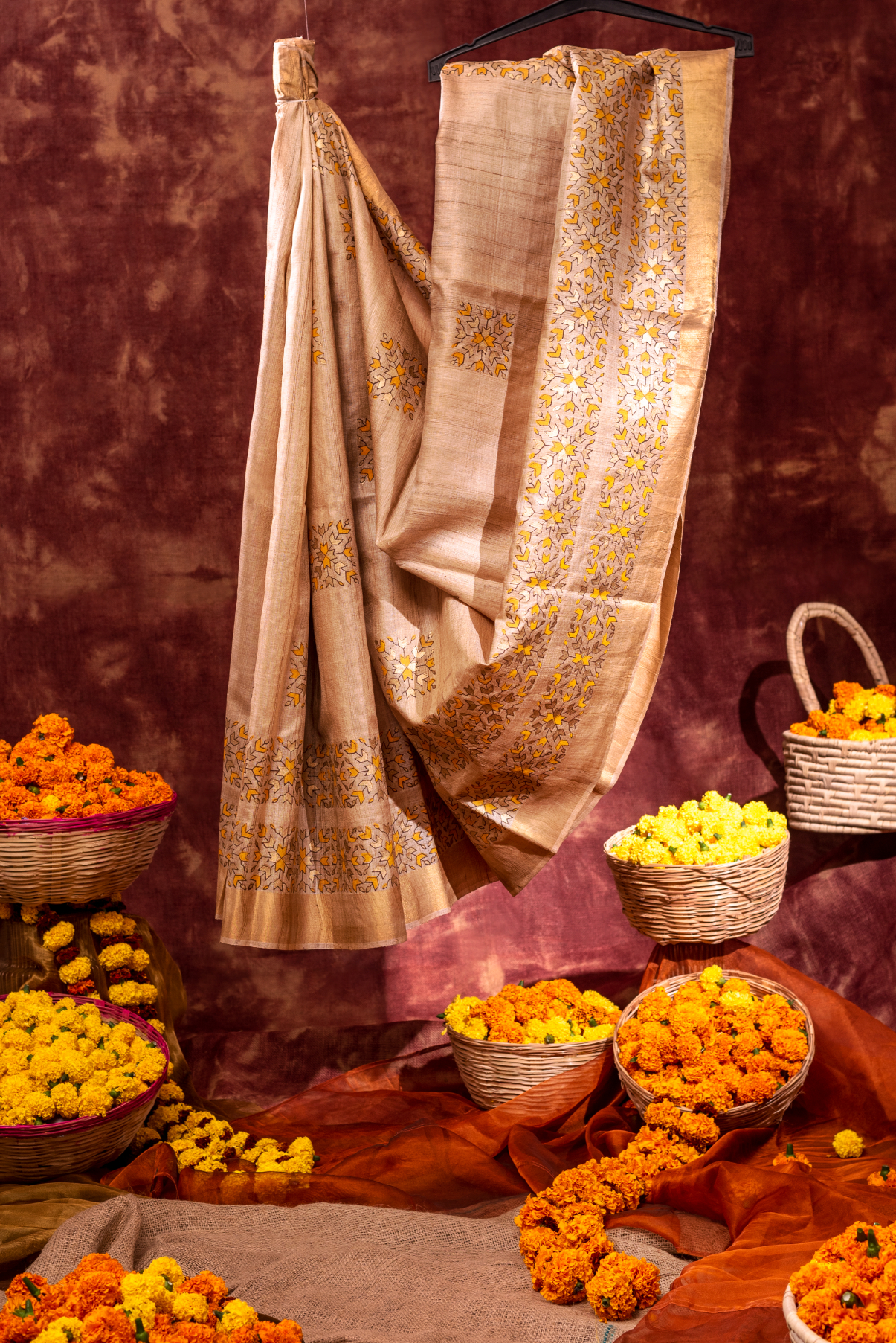 A traditional Indian saree draped elegantly with floral decorations in the background.