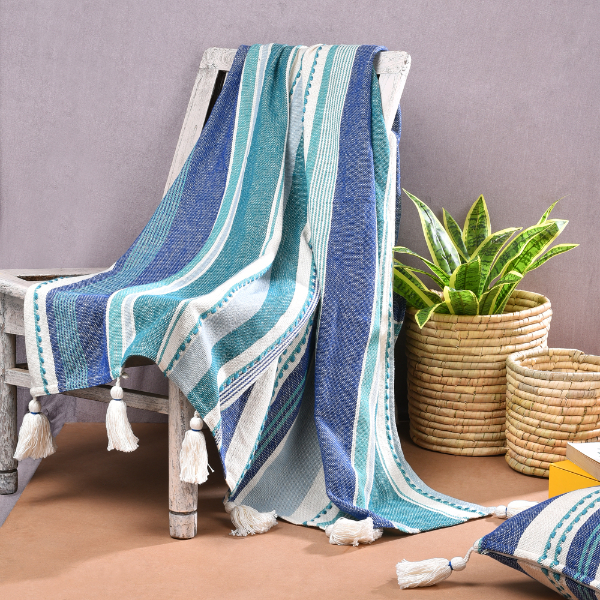 A blue and white striped throw blanket draped over a wooden chair with tassels at the ends.