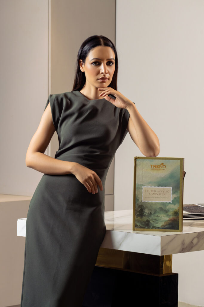 A woman in a green dress posing next to a book on a table.