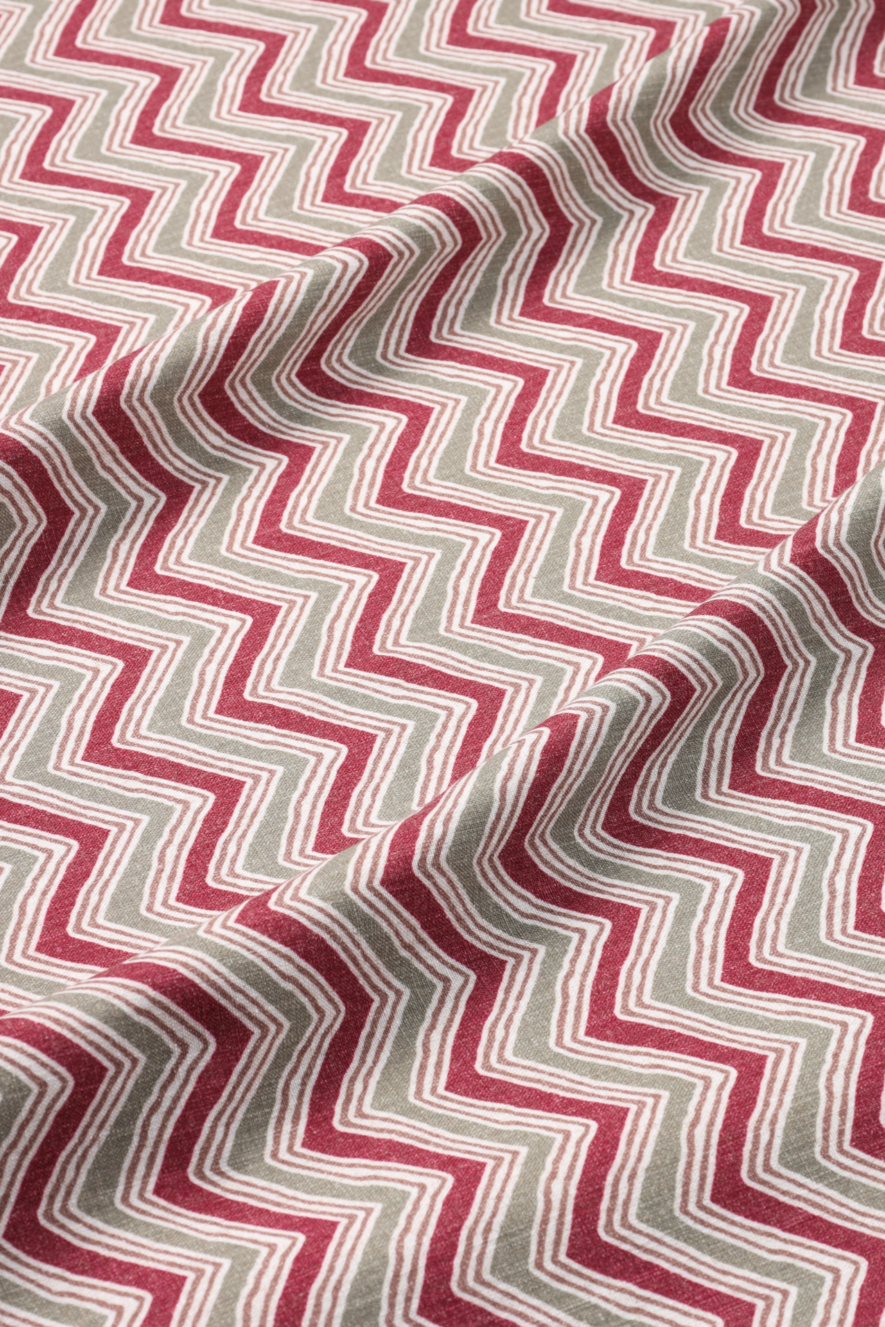 Fabric with a red and beige zigzag pattern featuring alternating lines and shapes.