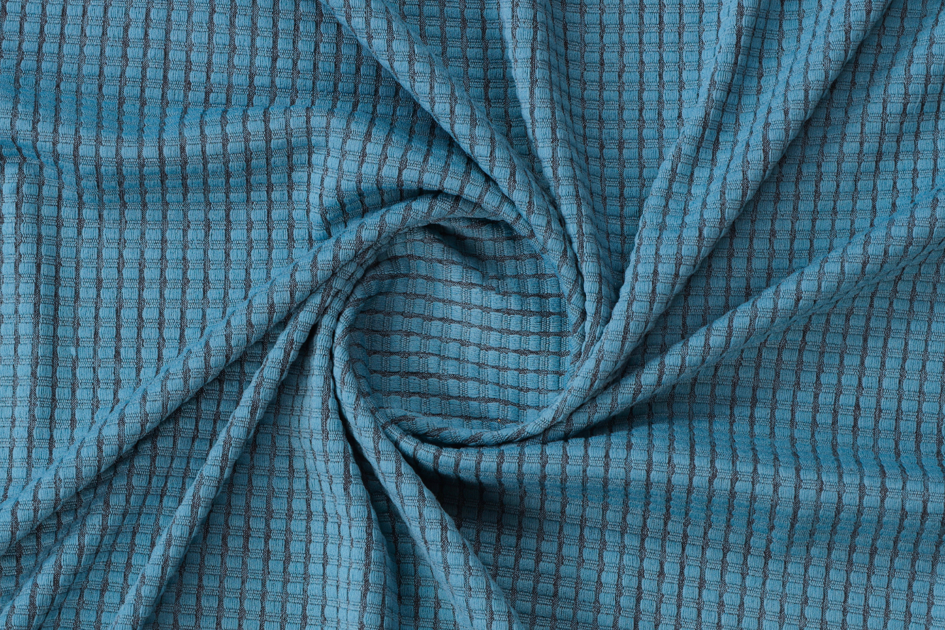 Close-up of textured blue fabric featuring a grid pattern in a spiral arrangement.