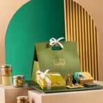 A Sovereign Collection gift hamper from Seven Seas Hotel sits beside sweets, jars, boxes, and plated desserts.