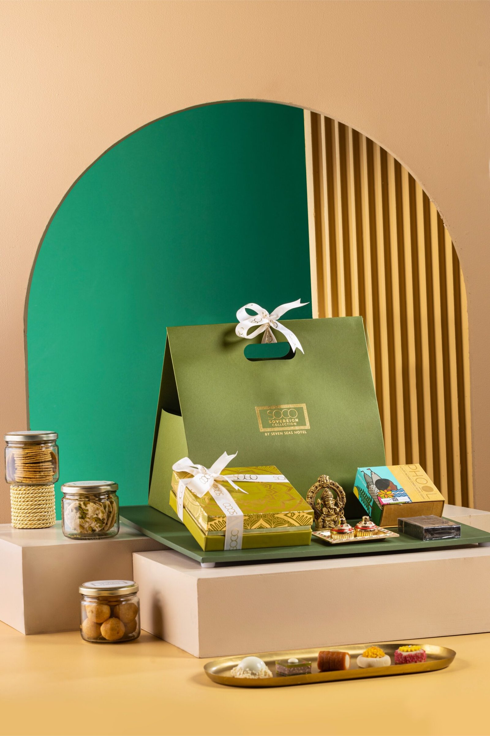 A Sovereign Collection gift hamper from Seven Seas Hotel sits beside sweets, jars, boxes, and plated desserts.