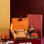 A Sovereign gift hamper with sweets, floral decorations, and colorful wrapped boxes arranged on red display blocks.