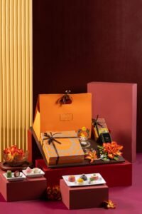 A Sovereign gift hamper with sweets, floral decorations, and colorful wrapped boxes arranged on red display blocks.