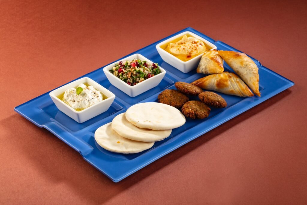 Assorted Indian snacks arranged on a blue platter with creamy dips, salad, fried pastries, croquettes, and flatbreads.